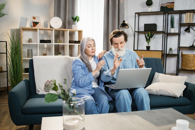 Pareja feliz de edad avanzada abrazándose usando una computadora portátil juntos