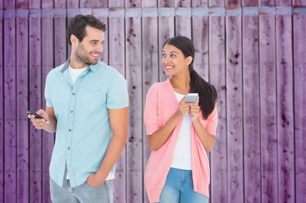 Pareja feliz enviando mensajes de texto contra el fondo de madera en púrpura