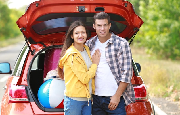 Pareja feliz con equipaje cerca del coche