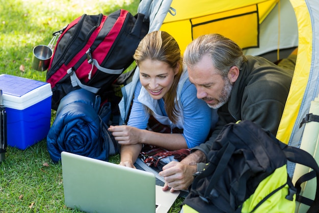 Pareja feliz excursionista usando laptop