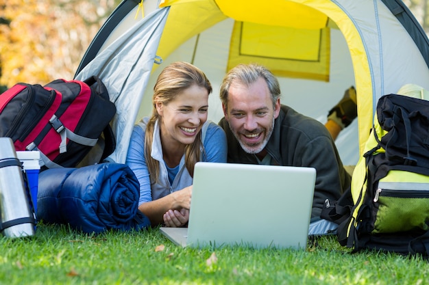 Pareja feliz excursionista usando laptop