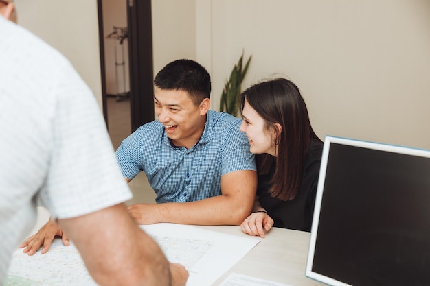 Una pareja feliz firma un contrato juntos en la oficina, un hombre y una mujer compran un apartamento y firman un contrato