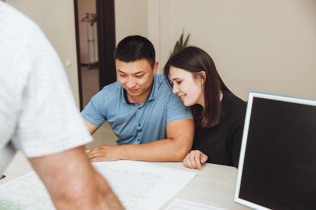 Una pareja feliz firma un contrato juntos en la oficina, un hombre y una mujer compran un apartamento y firman un contrato