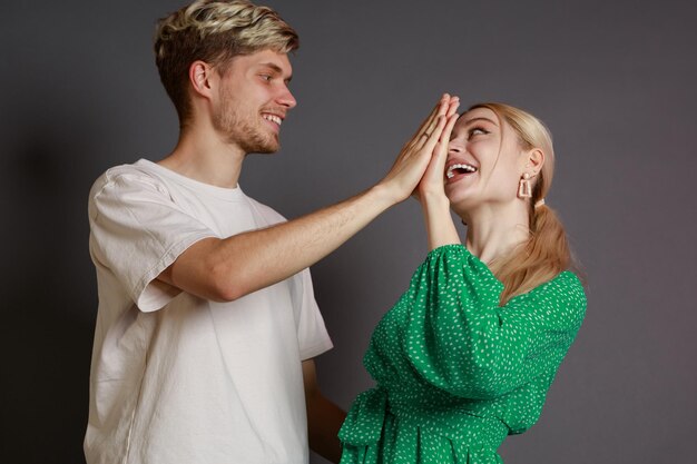 Una pareja feliz se para en un fondo gris y mantiene sus manos juntas