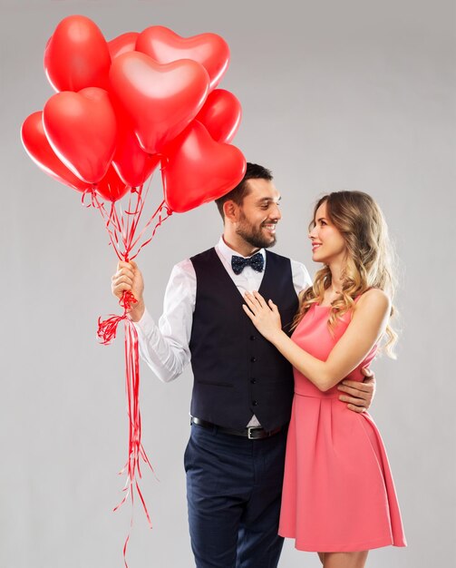 pareja feliz con globos en forma de corazón rojo