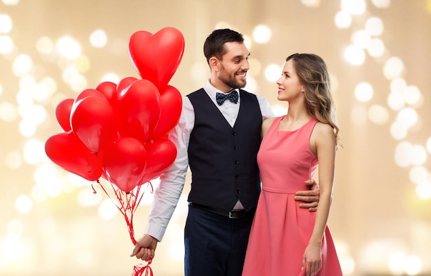 pareja feliz con globos en forma de corazón rojo