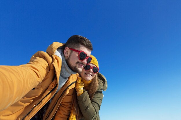 Pareja feliz haciendo selfie en un día soleado de invierno Espacio de copia de gran angular