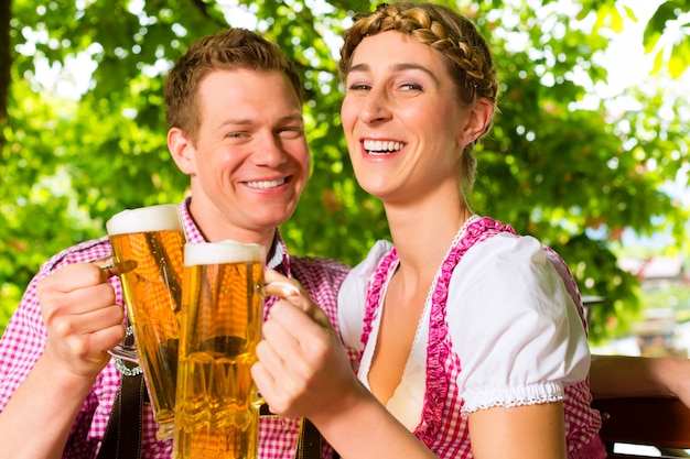 Pareja feliz en el jardín de la cerveza bebiendo cerveza