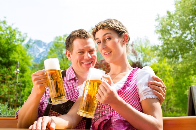 Pareja feliz en el jardín de la cerveza bebiendo cerveza