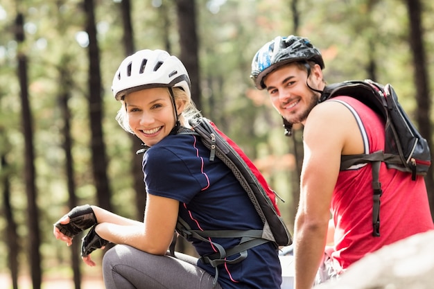 Pareja feliz joven motorista sentado en una roca