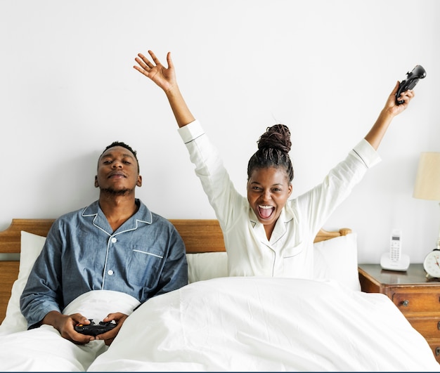 Una pareja feliz jugando videojuegos en la cama