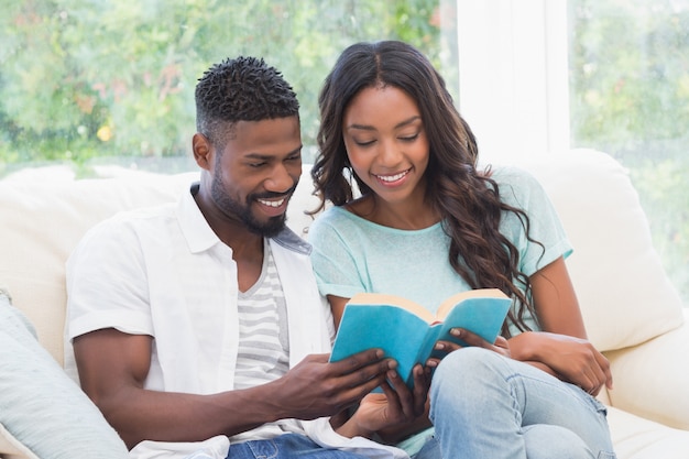 Pareja feliz leyendo en el sofá