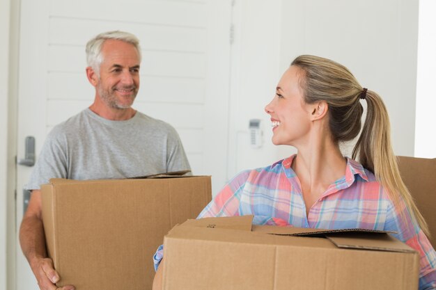 Foto pareja feliz llevando cajas de cartón en movimiento