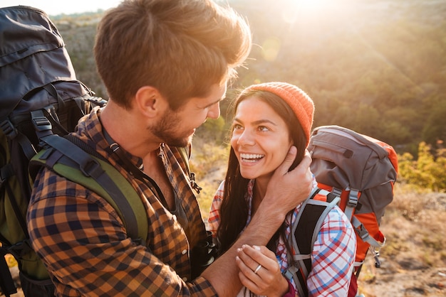 Pareja feliz con mochilas en las montañas