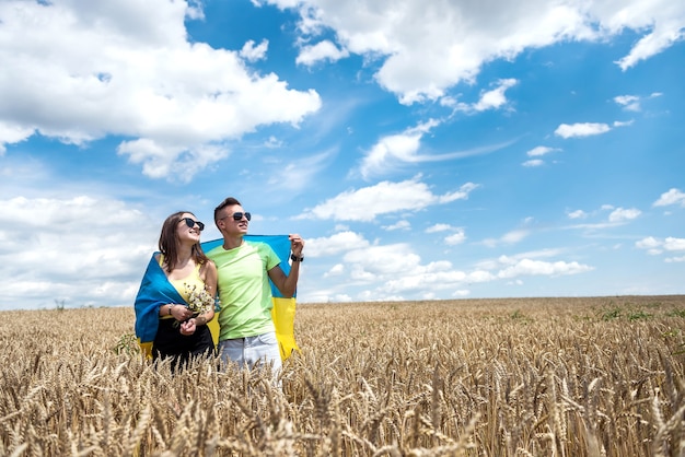 Foto pareja feliz de molda con bandera de ucrania en campo de trigo. estilo de vida