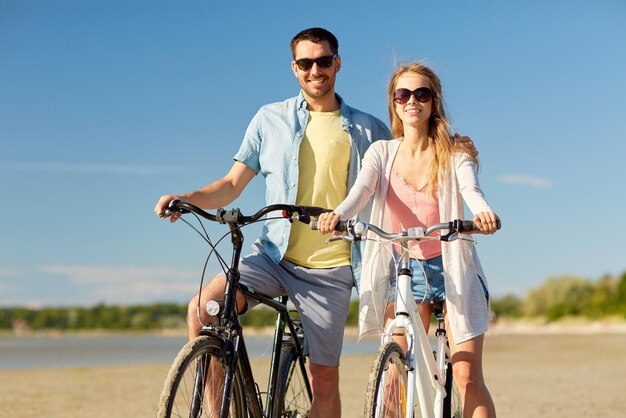 una pareja feliz montando bicicletas en la orilla del mar