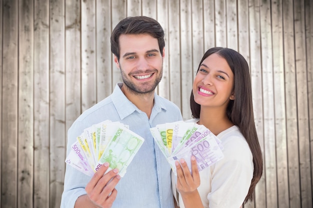 Pareja feliz mostrando su dinero contra el fondo de tablones de madera