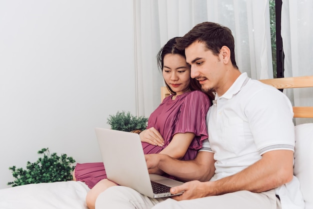 Foto pareja feliz mujer embarazada y esposo se quedan en casa en la sala de estar pareja feliz cuidando juntos