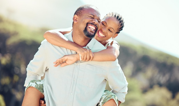 Pareja feliz y mujer negra recibiendo un paseo a cuestas de su esposo africano en unas vacaciones de verano en el campo Sonríe, relájate y viaja al aire libre en un parque de vacaciones de amor romántico y naturaleza pacífica