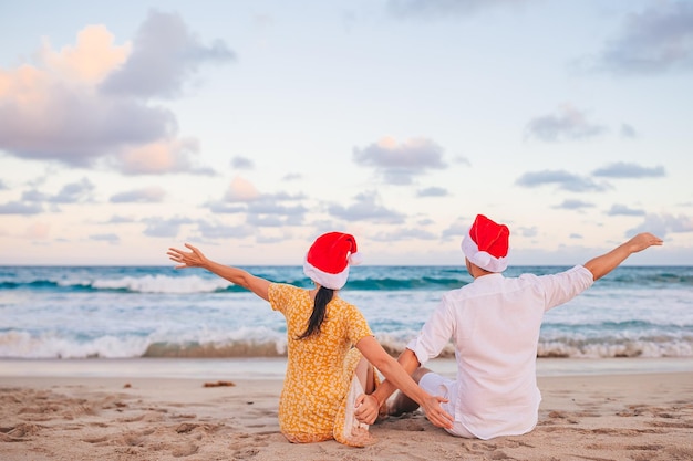 Pareja feliz de Navidad en sombreros de Santa en vacaciones en la playa