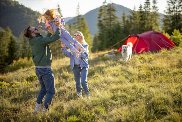 Una pareja feliz con una niña se divierte mientras viaja por las montañas