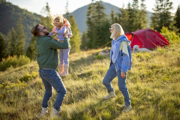 Una pareja feliz con una niña se divierte mientras viaja por las montañas