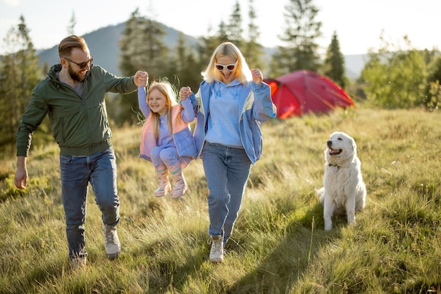 Una pareja feliz con una niña se divierte mientras viaja por las montañas