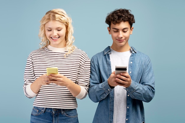 Una pareja feliz, un novio y una novia atractivos con teléfonos móviles, chateando y navegando juntos.