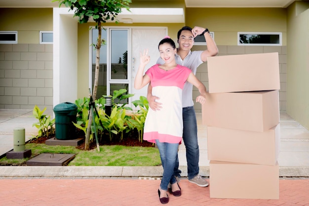 Una pareja feliz parada frente a su casa