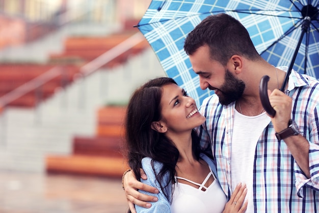 pareja feliz bajo el paraguas en la ciudad