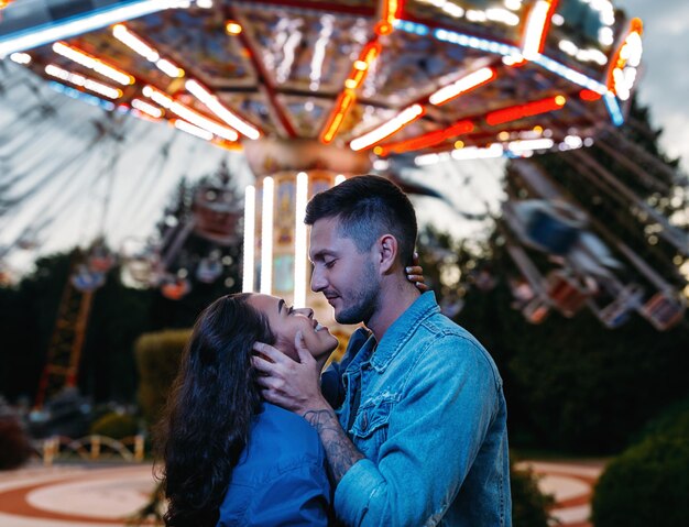 Pareja feliz en un parque de diversiones Pareja joven enamorada abrazándose