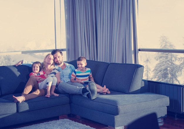 pareja feliz pasando tiempo con los niños usando una tableta en el sofá en casa