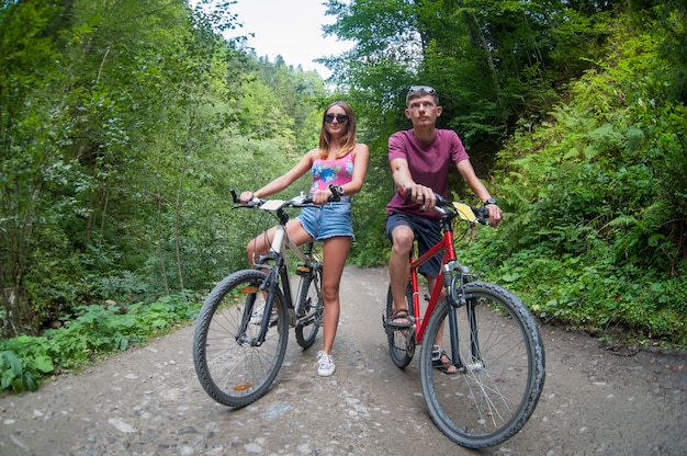 pareja feliz paseo en una carretera de asfalto de montaña en bicicletas