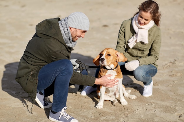 Foto pareja feliz con perro beagle en la playa de otoño