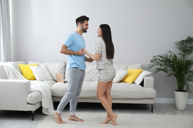 Pareja feliz en pijama bailando en casa