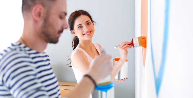 Pareja feliz pintando casa nueva renovación de casa nueva