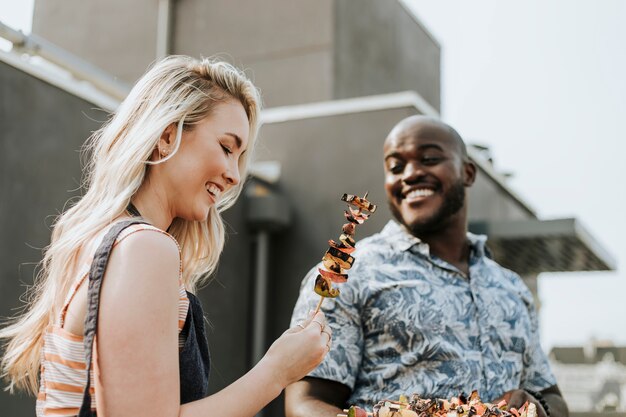 Pareja feliz preparando pinchos de barbacoa