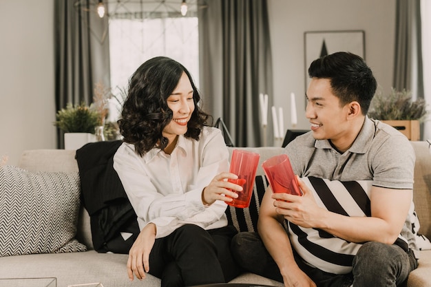 Una pareja feliz que aplaude las gafas se sienta en el sofá