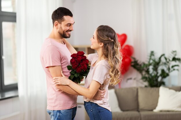 pareja feliz con un ramo de flores abrazándose en casa