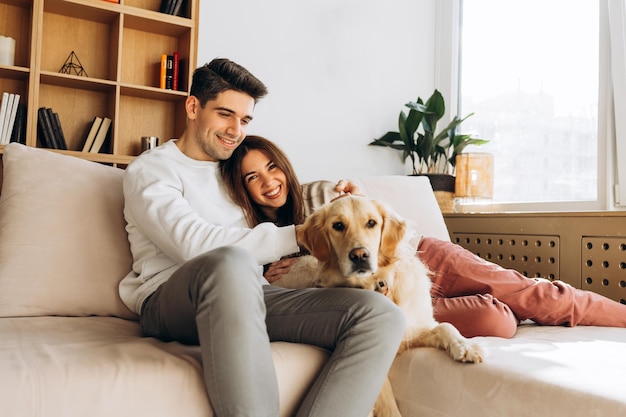Una pareja feliz relajándose en el sofá con un perro golden retriever en casa