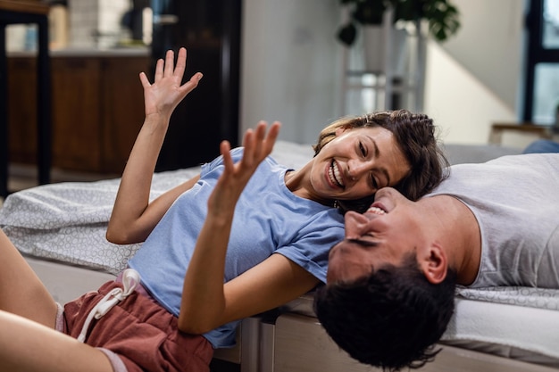 Una pareja feliz riendo juntos mientras la mujer habla de algo divertido en el dormitorio