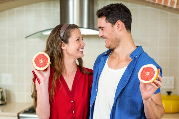 Pareja feliz con rodajas de naranja de sangre en la cocina