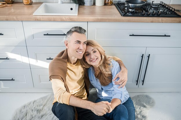 Una pareja feliz sentada en la cocina y luciendo alegre