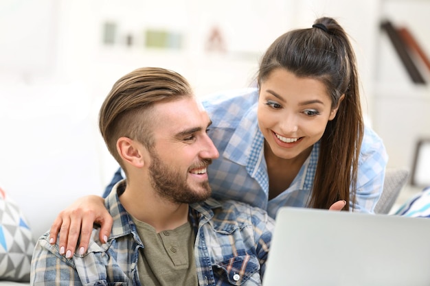 Pareja feliz sentada en la mesa y trabajando con una computadora portátil