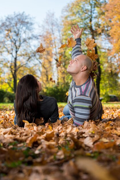 Pareja feliz sentados juntos en el bosque durante el otoño