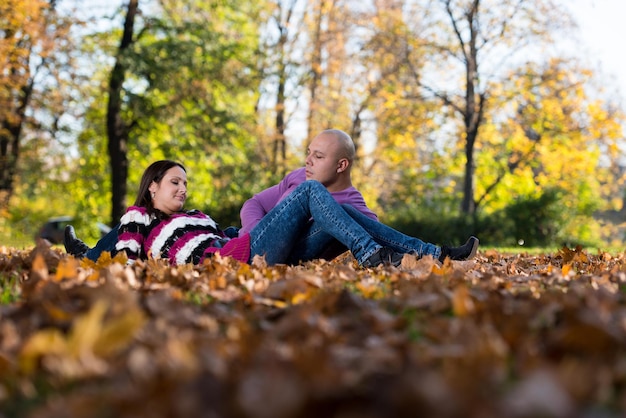 Pareja feliz sentados juntos en el bosque durante el otoño