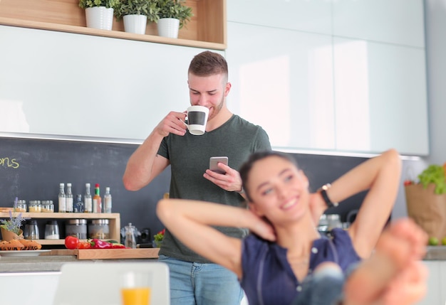 Pareja feliz con smartphone sentado en la cocina