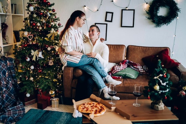 Pareja feliz en el sofá en casa disfrutando de Navidad