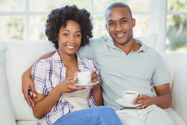 Pareja feliz en el sofá tomando café en la sala de estar