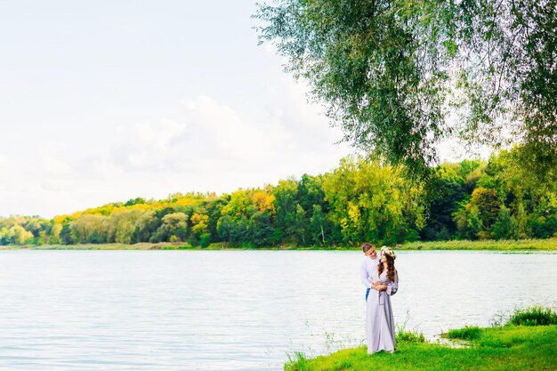 Pareja feliz y sonriente en el fondo de un hermoso lago y árboles de otoño